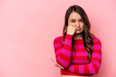 Pembe arka planda izole edilmiş genç beyaz kadın üzgün ve düşünceli, fotokopi alanına bakıyor..