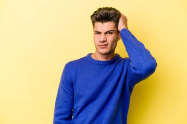 Sarı arka planda izole edilmiş genç beyaz adam yorgun ve uykulu bir şekilde ellerini başının üstünde tutuyor..