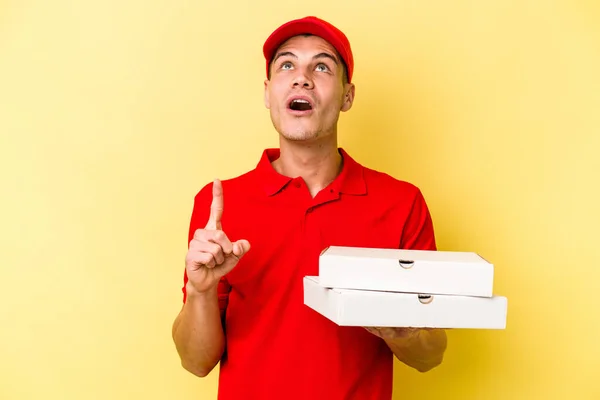 Young Delivery Caucasian Man Holding Pizzas Isolated Yellow Background Pointing — ストック写真