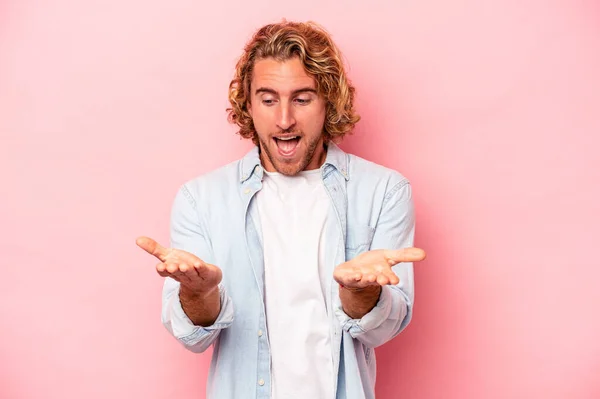 Jonge Blanke Man Geïsoleerd Roze Achtergrond Met Iets Met Handpalmen — Stockfoto