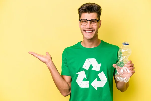 Mladý Kavkazský Muž Drží Láhev Plastu Recyklaci Izolované Žlutém Pozadí — Stock fotografie