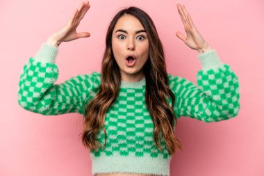 Pembe arka planda izole genç beyaz kadın zaferi ya da başarıyı kutluyor, şaşırıyor ve şok oluyor..