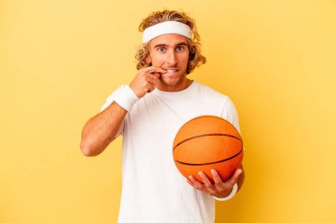 Genç basketbolcu beyaz adam sarı arka planda izole edilmiş tırnak yiyor, gergin ve çok endişeli..