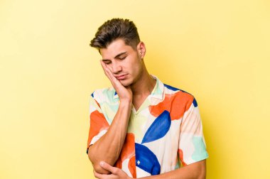 Sarı arka planda izole edilmiş genç beyaz adam sıkılmış, yorgun ve dinlenmeye ihtiyacı var..