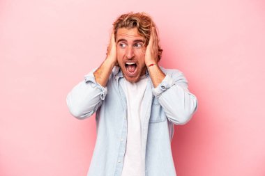 Kafkasyalı genç adam pembe arka planda izole edilmiş kulakları kulaklarıyla kapatıyor çok fazla ses duymamaya çalışıyor..