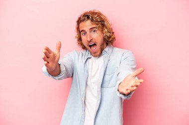 Pembe arka planda izole edilmiş genç beyaz adam kameraya sarıldığı için kendinden emin hissediyor..