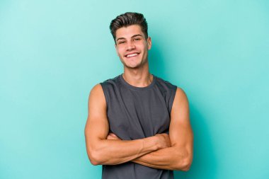 Mavi arka planda izole edilmiş genç beyaz adam mutlu, güler yüzlü ve neşeli.