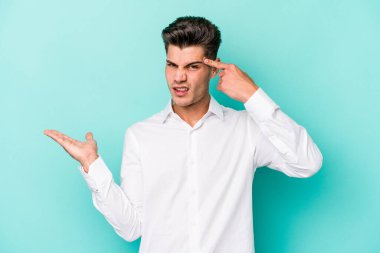 Mavi arka planda izole edilmiş genç beyaz adam işaret parmağıyla bir hayal kırıklığı jesti gösteriyor..