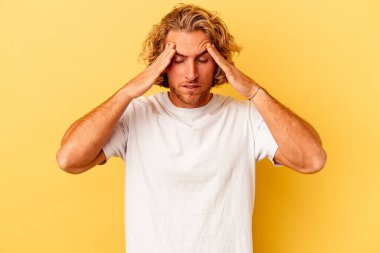 Kafkasyalı genç adam sarı arka planda izole edilmiş, başı ağrıyor, yüzüne dokunuyor..