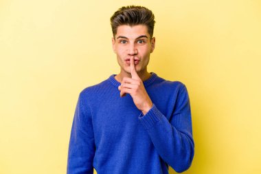 Sarı arka planda izole edilmiş genç beyaz bir adam ya sır saklıyor ya da sessizlik istiyor..