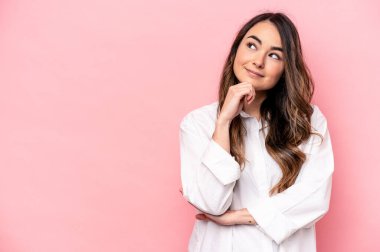 Pembe arka planda soyutlanmış beyaz bir kadın şüpheli ve şüpheci bir ifadeyle yana bakıyor..