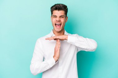 Mavi arka planda izole edilmiş genç beyaz bir adam bir mola hareketi gösteriyor..