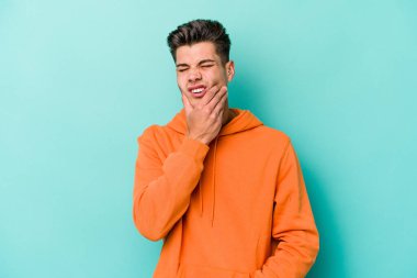 Mavi arka planda izole genç beyaz adam güçlü bir diş ağrısı, azıdişi ağrısı var..