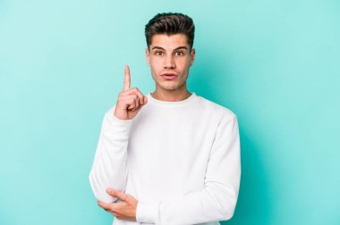 Kafkasyalı genç adam mavi arka planda izole edildi. Harika bir fikri var, yaratıcılık kavramı..