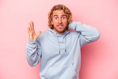 Pembe arka planda izole edilmiş genç beyaz adam öfkeyle bağırıyor..