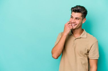 Mavi arka planda izole edilmiş genç beyaz adam rahatlamış bir şeyin fotokopi odasına baktığını düşünüyor..