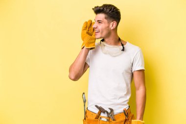 Genç elektrikçi, sarı arka planda izole edilmiş beyaz bir adam gizli bir fren haberinin olduğunu söylüyor.