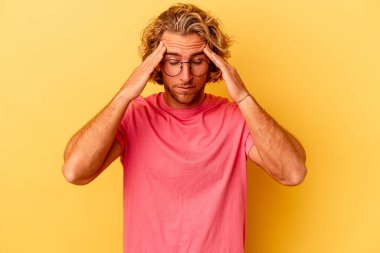 Sarı arka planda izole edilmiş genç beyaz adam tapınaklara dokunuyor ve baş ağrısı çekiyor..