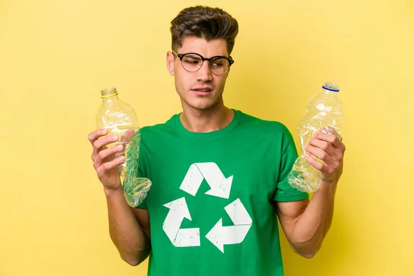 Young Caucasian Man Holding Bottle Plastic Recycle Isolated Yellow Background — Stok fotoğraf