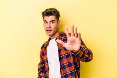 Sarı arka planda izole genç beyaz adam yakın bir tehlike nedeniyle şoka uğruyor