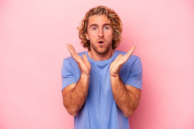 Pembe arka planda izole edilmiş genç beyaz adam şaşırdı ve şok oldu..