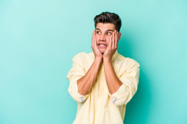 Kafkasyalı genç adam mavi arka planda izole edilmiş korkmuş ve korkmuş..