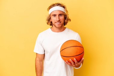 Genç basketbolcu beyaz adam sarı arka planda izole edilmiş mutlu, güler yüzlü ve neşeli..