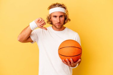 Genç basketbolcu, sarı arka planda izole edilmiş, hoşlanmadığı bir hareket gösteren beyaz bir adam. Anlaşmazlık konsepti.