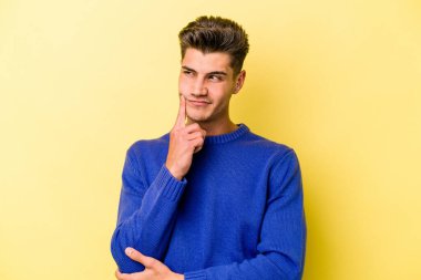 Kafkasyalı genç bir adam sarı arka planda izole edilmiş. Bir strateji planlıyor, bir iş yolu düşünüyor..