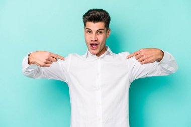 Kafkasyalı genç adam mavi arka planda izole edildi. Parmakları aşağıda, olumlu bir his var..