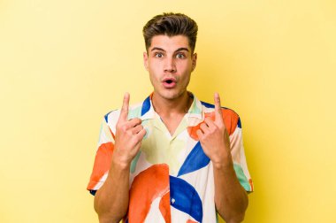 Sarı arka planda izole edilmiş beyaz bir adam ağzı açık bir şekilde üst tarafı işaret ediyor..