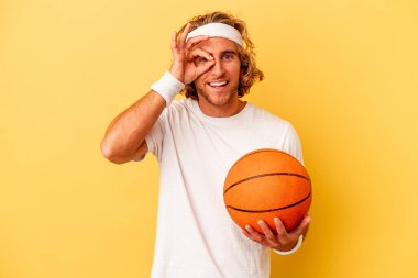 Genç basketbolcu Kafkasyalı adam sarı arka planda izole edilmiş..