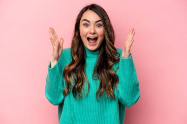 Pembe arka planda izole genç beyaz kadın zaferi ya da başarıyı kutluyor, şaşırıyor ve şok oluyor..