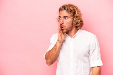 Pembe arka planda izole edilmiş genç beyaz adam gördüğü bir şey yüzünden şoka uğruyor..