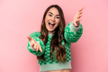 Pembe arka planda izole edilmiş genç beyaz kadın kameraya sarıldığı için kendinden emin..