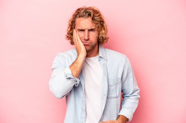 Pembe arka planda izole edilmiş genç beyaz adamın yanakları şişer, yorgun bir ifadesi vardır. Yüz ifadesi kavramı.