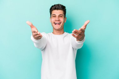 Mavi arka planda izole edilmiş genç beyaz adam kameraya sarıldığı için kendinden emin hissediyor..