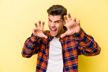 Sarı arka planda izole edilmiş genç beyaz adam gergin elleriyle çığlık atıyor..