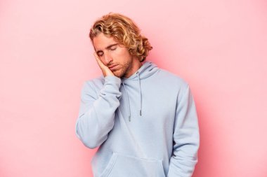Pembe arka planda izole edilmiş genç beyaz adam sıkılmış, yorgun ve dinlenmeye ihtiyacı var..