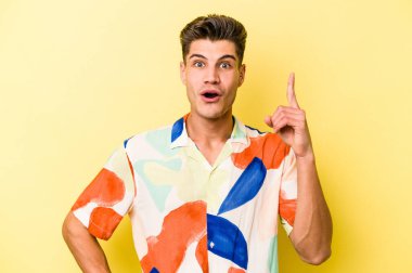 Sarı arka planda izole edilmiş genç beyaz adamın bir fikri var, ilham verici bir kavram..