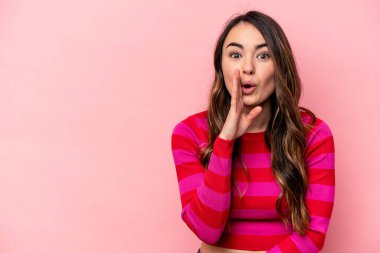 Pembe arka planda izole edilmiş genç beyaz kadın gizli bir sıcak fren haberi veriyor ve yana bakıyor.