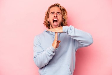 Pembe arka planda izole edilmiş genç beyaz adam bir mola hareketi gösteriyor..