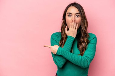 Pembe arka planda izole edilmiş genç beyaz kadın yan tarafı gösteriyor.