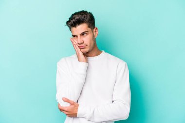 Mavi arka planda izole edilmiş, sıkılmış, yorgun ve dinlenmeye ihtiyacı olan genç beyaz bir adam..