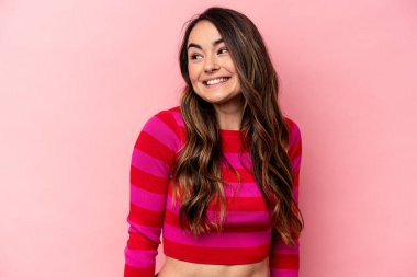 Pembe arka planda izole edilmiş genç beyaz kadın gülüyor ve gözlerini kapıyor, rahatlamış ve mutlu hissediyor..