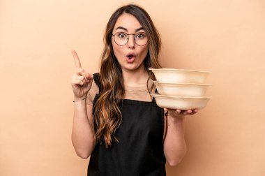 Beyaz tenli genç bir kadın bej arka planda saklanmış vaziyette harika bir fikri, yaratıcılık kavramı var..