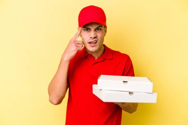 Sarı arka planda pizza tutan beyaz bir adam işaret parmağıyla hayal kırıklığına uğradığını gösteriyor..