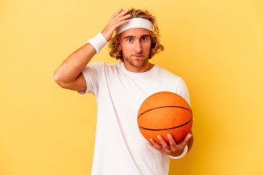 Young basketball player caucasian man isolated on yellow background being shocked, she has remembered important meeting.