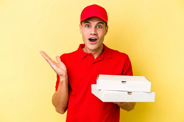 Young Delivery Caucasian Man Holding Pizzas Isolated Yellow Background Surprised — ストック写真