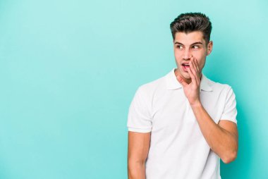 Mavi arka planda izole edilmiş genç beyaz bir adam gizli bir sıcak fren haberi veriyor ve yana bakıyor.